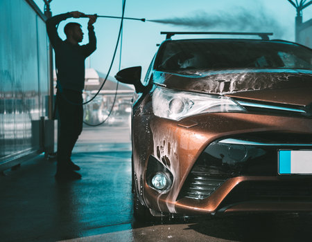 Man washing car in self serve car wash. Cleaning car using high pressure water. Car smart washの写真素材