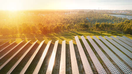 Aerial view of ecology solar power station panels farm on sunset or sunrise. Rows of modern...