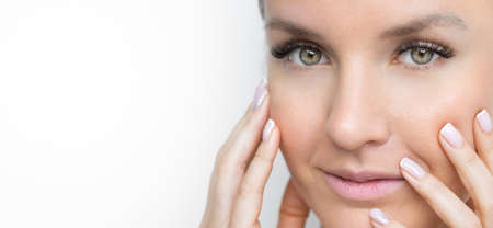 Close up of beautiful young woman with clean fresh skin and french manicure holding her cheeks. Female beauty face care. Facial treatment. Cosmetology, beauty and spa. Copy spaceの写真素材