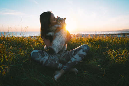 Cute girl kisses her lovely funny beautiful cat outdoors at sunset. Cat with owner. Love for cats.