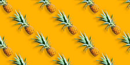 Seamless pattern of ripe pineapples isolated on orange background. Summer exotic fruitの写真素材