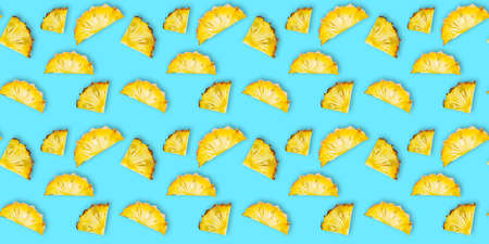 Seamless pattern of fresh ripe pineapple slices isolated on cyan background. Top view. Exotic tropical fruit summer conceptの写真素材
