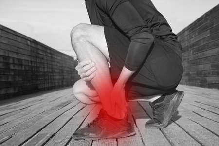 Running and workout injuries. Athlete suffering from ankle pain or achilles injury. Ankle twist sprain accidentの写真素材