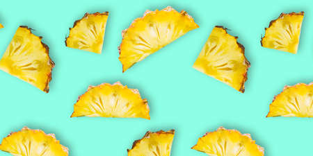 Pattern of fresh ripe pineapple slices isolated on cyan background. Top view. Exotic tropical fruit summer conceptの写真素材