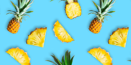 Seamless pattern of ripe whole pineapples and slices isolated on blue background. Tropical fruit...