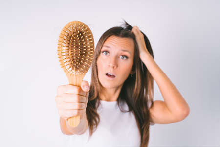 Woman with hair brush with damaged hair. Hair loss problem. Hair falling outの写真素材