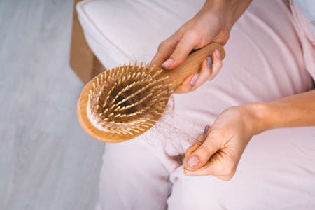 Woman taking her hair from hairbrush. Hair loss problem. Bad hair falling outの写真素材