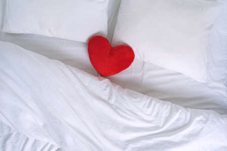 Top view of white bed with pillows and read heart toyの写真素材