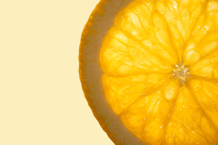 Slice of fresh juicy orange fruit close up on light orange copy space background. Macro photography concept.の写真素材