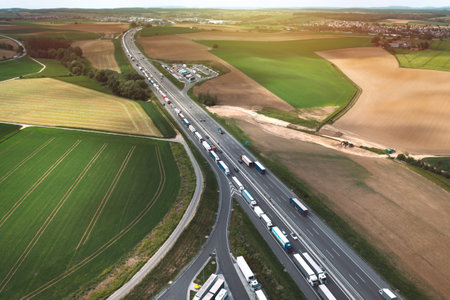 Aerial view of logistic traffic and parking lots full of trucks on highway with fields in Poland....