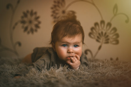 Cute baby girl in brown clothes close up crawling on bed. Adorable kid portrait. 5 month old child