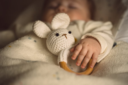 Sleeping newborn baby with a soft bunny toy under the blanket in warm, cozy sunlight. Childhood and parenting concept.の写真素材