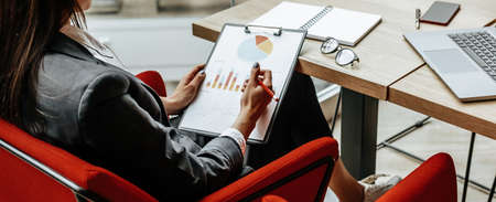 Business woman checks charts and refreshes financial progress. The girl analyzes the business model in the workplace.の写真素材