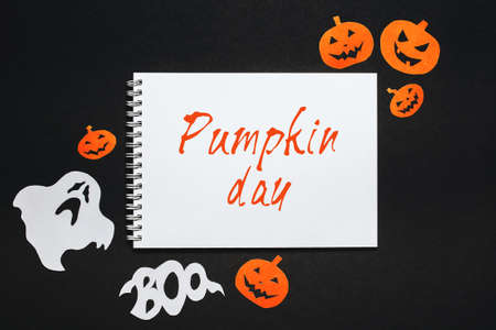 Happy halloween holiday concept. Notepad with text Pumpkin day on black and orange background with bats, pumpkins and ghostsの写真素材