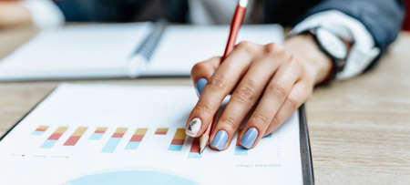 Business woman checks charts and refreshes financial progress. The girl analyzes the business model in the workplace.の写真素材