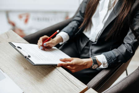 Young girl office worker or business lady signs documents. Concentrated businesswoman working with papers. Business conceptの写真素材
