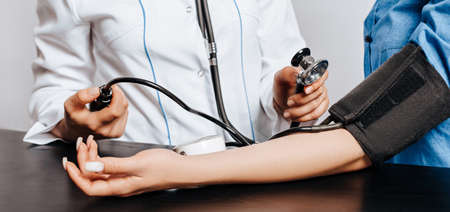 Doctor measures blood pressure with a tonometer to a woman patient at a medical appointment in a clinicの写真素材