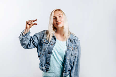Young beautiful blonde girl standing over gray isolated background smiling and confident gesturing...
