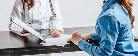 Woman at doctor at reception to check health at table on white isolated backgroundの写真素材