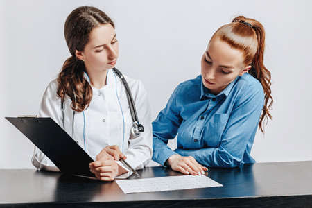 Woman at doctor at reception to check health at table on white isolated backgroundの写真素材