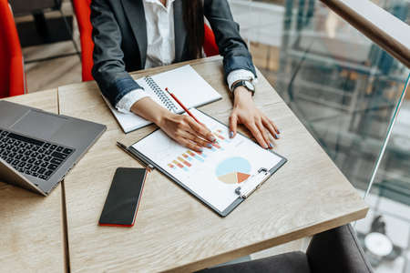 Business woman checks charts and refreshes financial progress. The girl analyzes the business model in the workplace.の写真素材