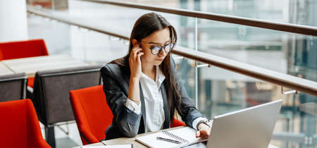 Girl works on a laptop in the workplace. Successful business woman creates a startup and makes decisions.の写真素材