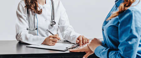 Woman at doctor at reception to check health at table on white isolated backgroundの写真素材