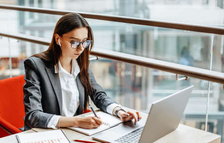 Girl works on a laptop in the workplace. Successful business woman creates a startup and makes decisions.の写真素材