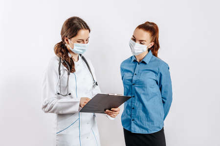 Woman patient at doctor in masks at reception to check health on white isolated backgroundの写真素材