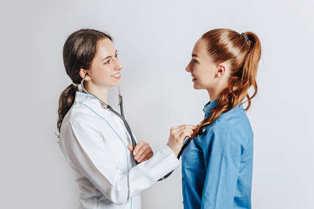 Doctor checking health of woman patient with stethoscope on white isolated backgroundの写真素材