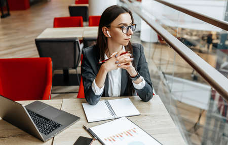 Girl works on a laptop in the workplace. Successful business woman creates a startup and makes decisions.の写真素材