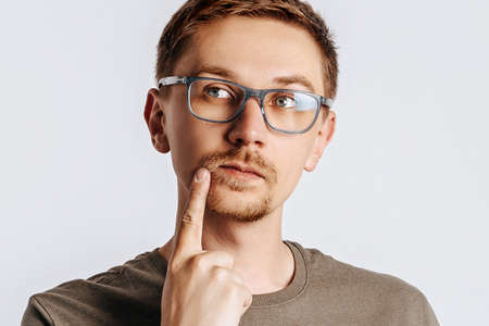 Young handsome man with glasses a brunette beard. Student, worker, businessman posing for photo isolated on gray background. Place for advertising.の写真素材