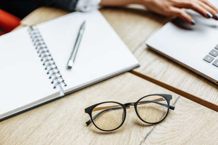 Glasses at the workplace in the office near the laptop and notepad. Business hours