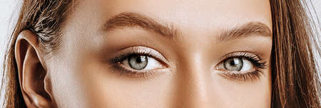View of a beautiful young brunette girl. Green female eyes with natural makeup. The woman looks into the camera.の写真素材