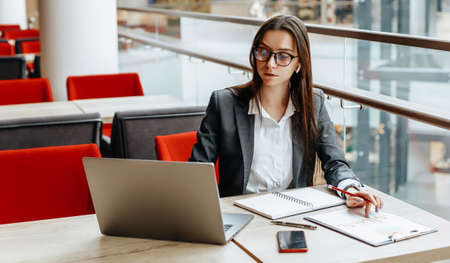 Girl works on a laptop in the workplace. Successful business woman creates a startup and makes decisions.の写真素材