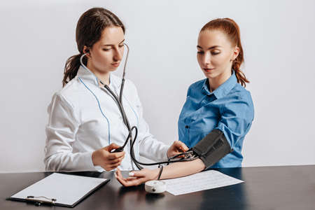 Doctor measures blood pressure with a tonometer to a woman patient at a medical appointment in a clinicの写真素材