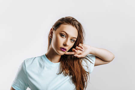 Beautiful young brunette girl with green eyes with long hair with fashion makeup with purple lips on...