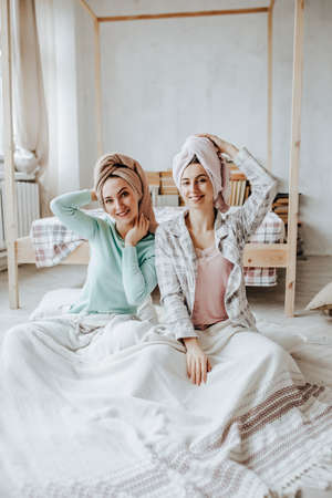 Two girls make homemade face and hair beauty masks. Cucumbers for the freshness of the skin around the eyes. Women take care of youthful skinの写真素材
