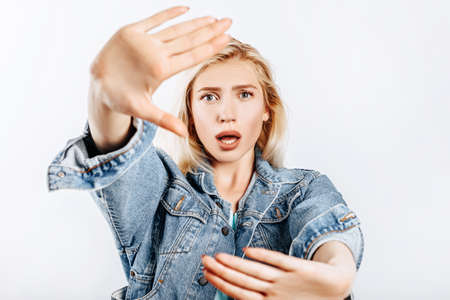 Beautiful young girl unhappy frown and says stop with a hand gesture on gray isolated backgroundの写真素材