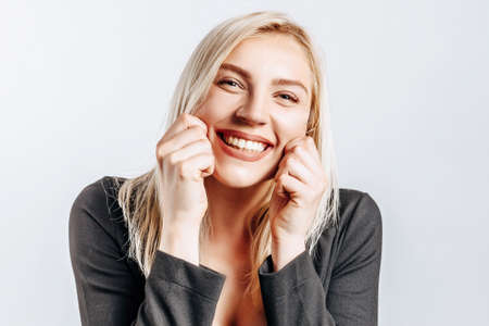 Beautiful happy young girl smiles on gray isolated backgroundの写真素材