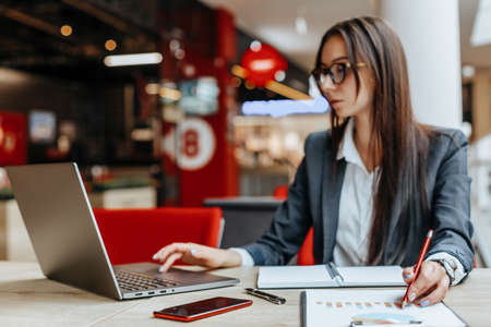 Girl works on a laptop in the workplace. Successful business woman creates a startup and makes decisions.の写真素材