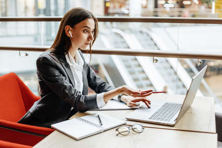 Girl works on a laptop in the workplace. Businesswoman is shocked by the crisis. Successful woman creates a startup and makes decisions.の写真素材
