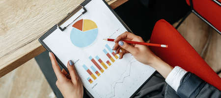 Business woman checks charts and refreshes financial progress. The girl analyzes the business model in the workplace.の写真素材