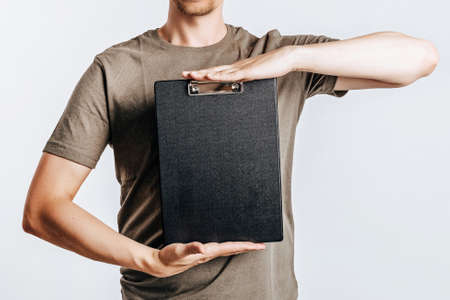 Young handsome man holding folder for papers with documents, student, worker looks data information, posing for photo isolated on gray background. Place for advertising.の写真素材