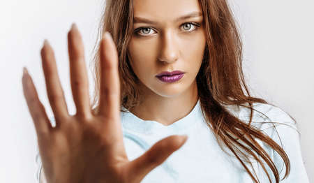 Stop. Enough. Young beautiful girl stretches out her hand to the camera to stop the effect. Woman...