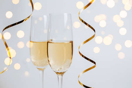 Two glasses of champagne with lights and ribbons on  whiteの写真素材