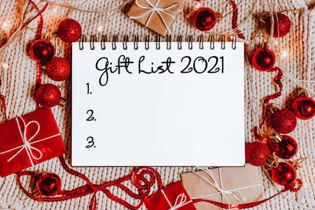 Merry christmas and merry new year concept with gift boxes, toys and notebook with text Gift List 2021の写真素材