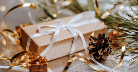 Christmas gifts in lights with pine cones and fir branches in a festive new year atmosphere on a...