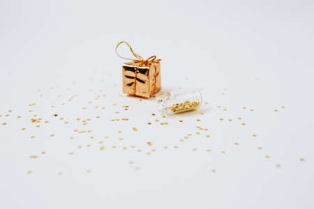 Spangles of gold and silver are scattered from bottles and a gift on a white background