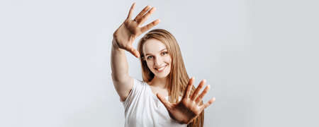 Young beautiful girl smiling and pulling her hands towards camera on gray isolated backgroundの写真素材